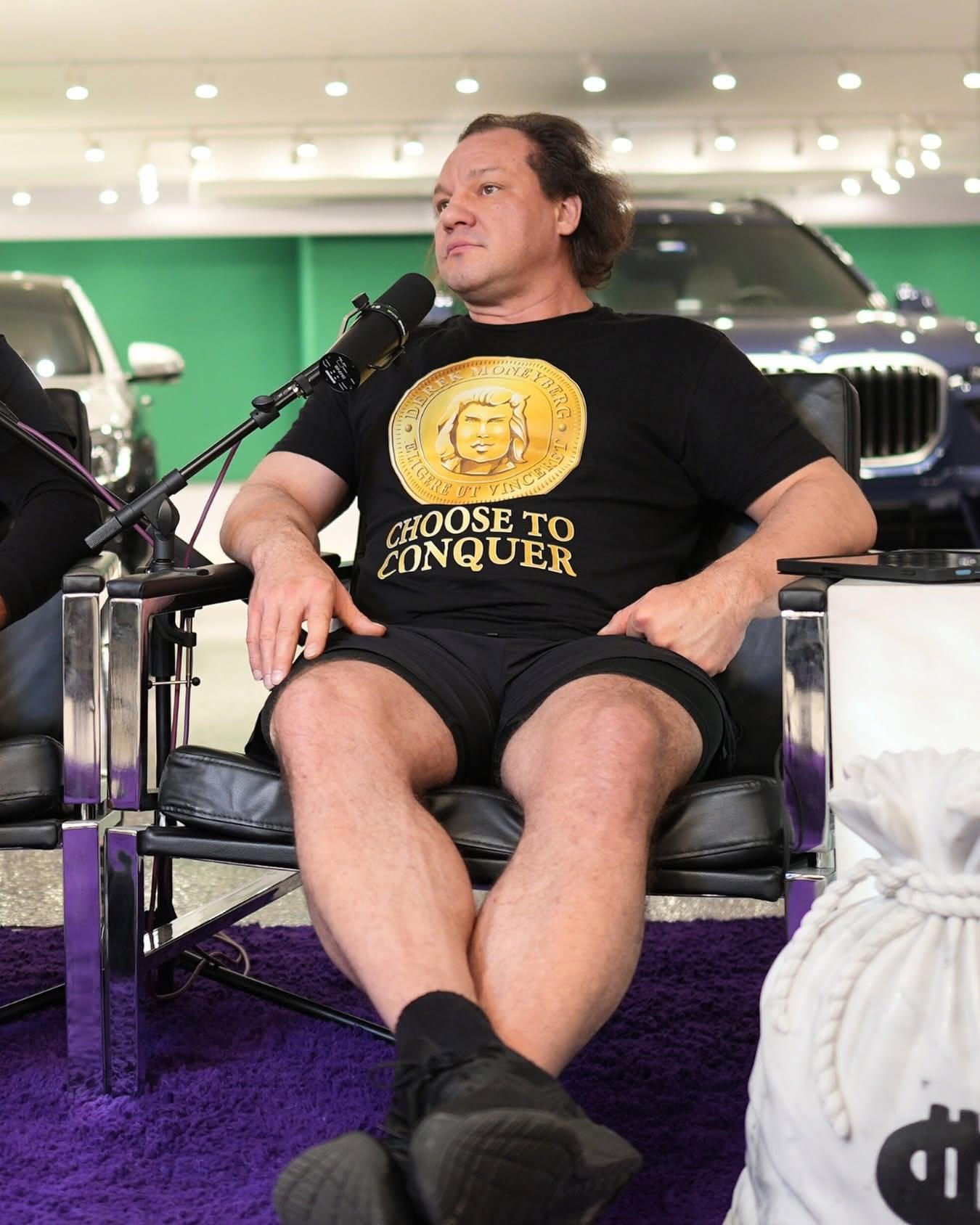 Derek Moneyberg seated at a microphone